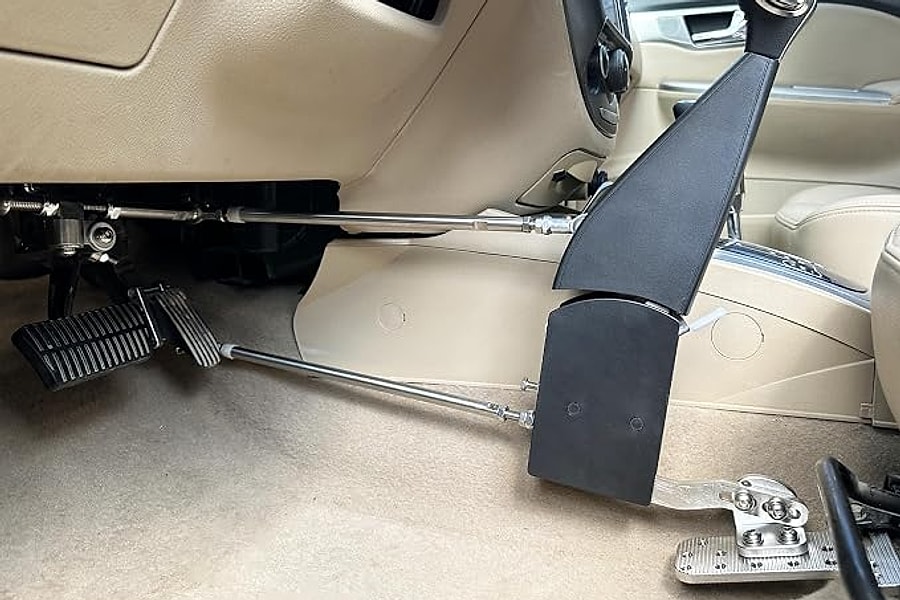 A left foot accelerator assembly and hand control lever fitted in the driver's footwell of a car